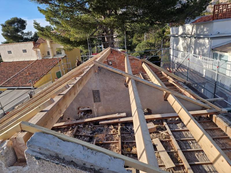 Pose de la nouvelle charpente en bois avec des poutres et chevrons à Marseille 